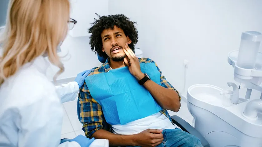 A patient holding his jaw in discomfort during a dental emergency.